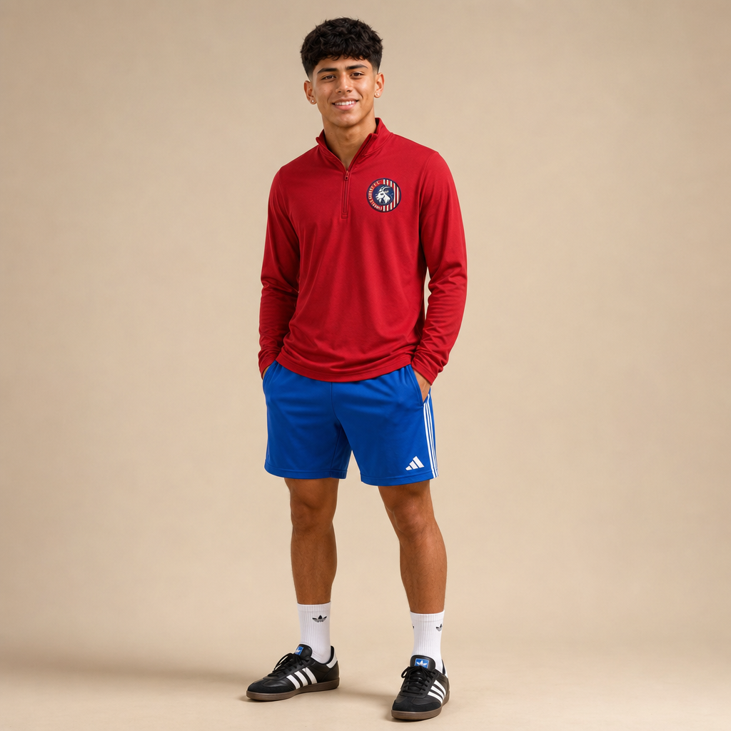 Soccer player wearing the Lindale Chivas Quarter-Zip Pullover in Red, worn untucked over royal blue soccer shorts