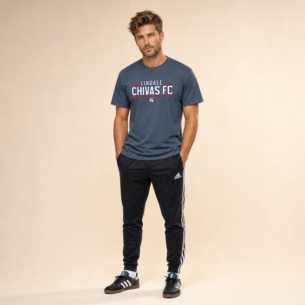 Man wearing the Lindale Chivas Wordmark Tee in Legion Blue, worn untucked over soccer pants with Adidas Sambas