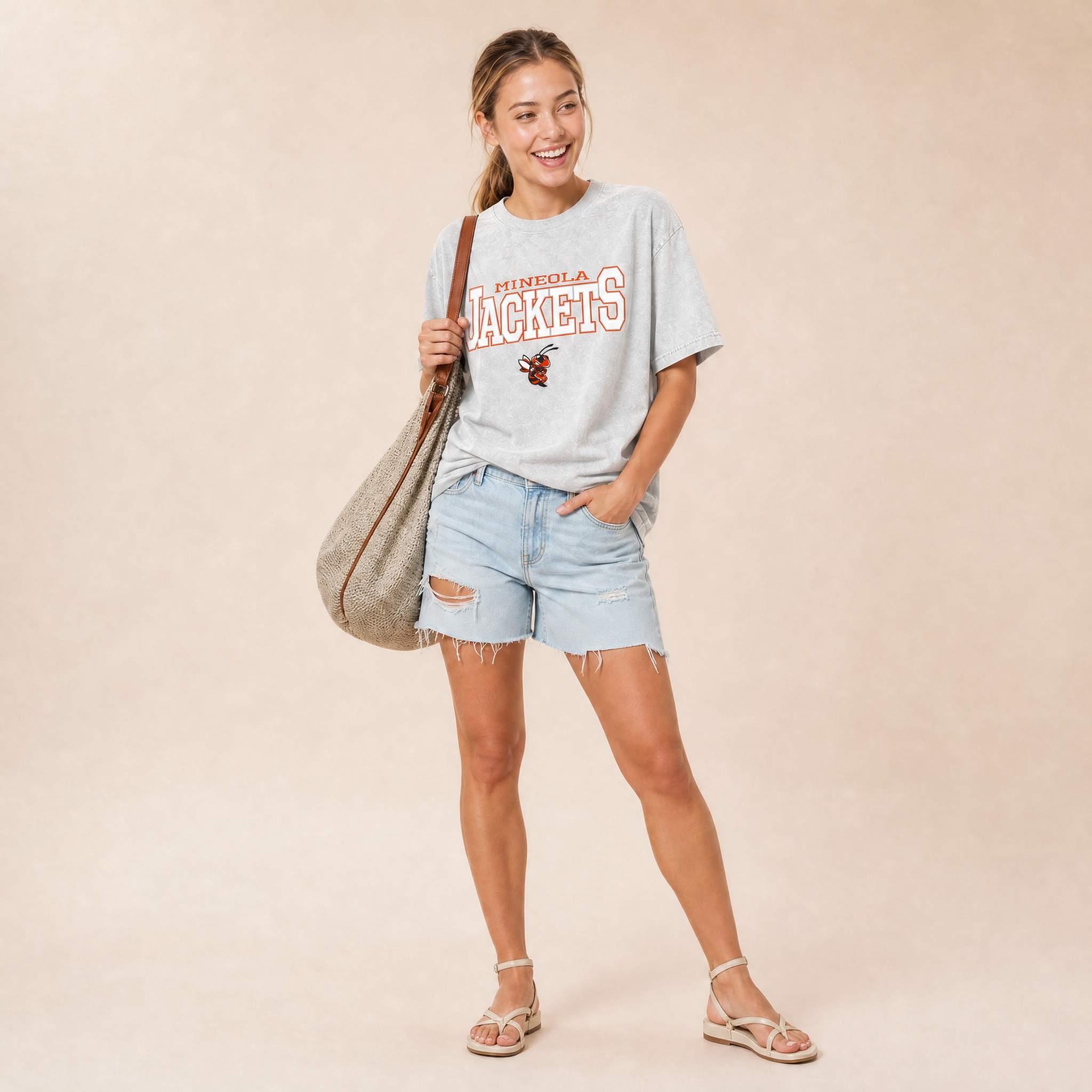 Mineola Jackets Snow Washed Tee in light gray — Mineola Jackets lockup and yellowjacket mascot in orange and white, worn by a model
