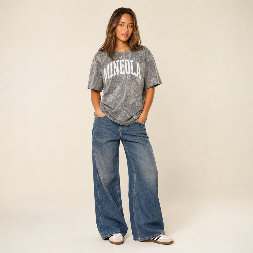Mineola Premium Camo Tee — MINEOLA in a white varsity arch on grey Deadwood Tree Camo, worn by a model